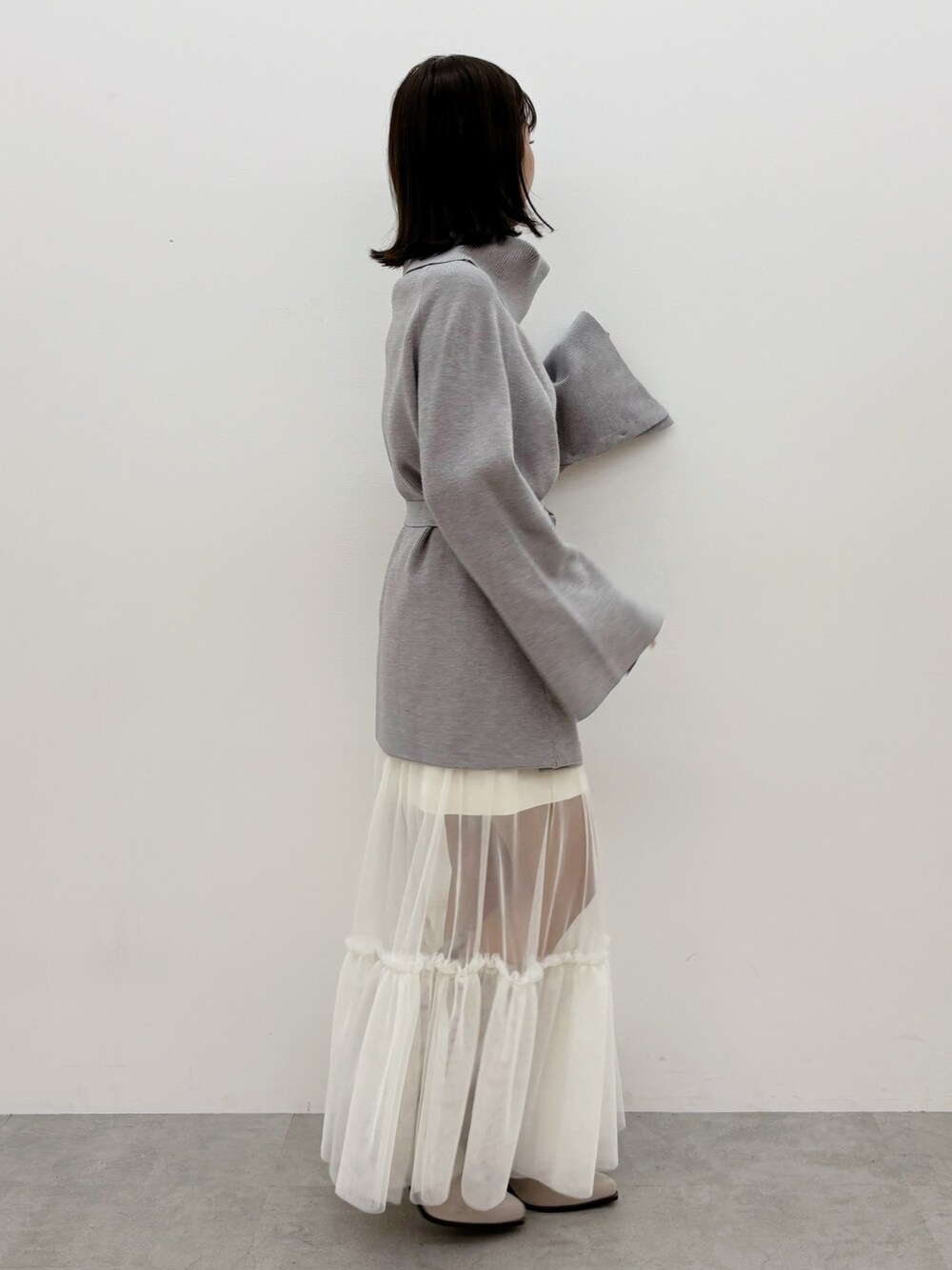 グレー系のニット/セーター、グレー系のブーツ、ホワイト系のスカートを着用したレディースの秋コーディネートの2枚目の写真