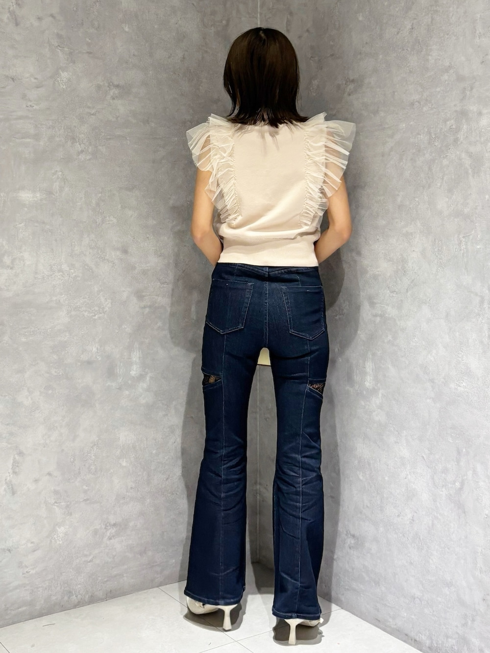 ブルー系のデニムパンツ、ピンク系のニット/セーター、ホワイト系のパンプスを着用したレディースの春コーディネートの3枚目の写真