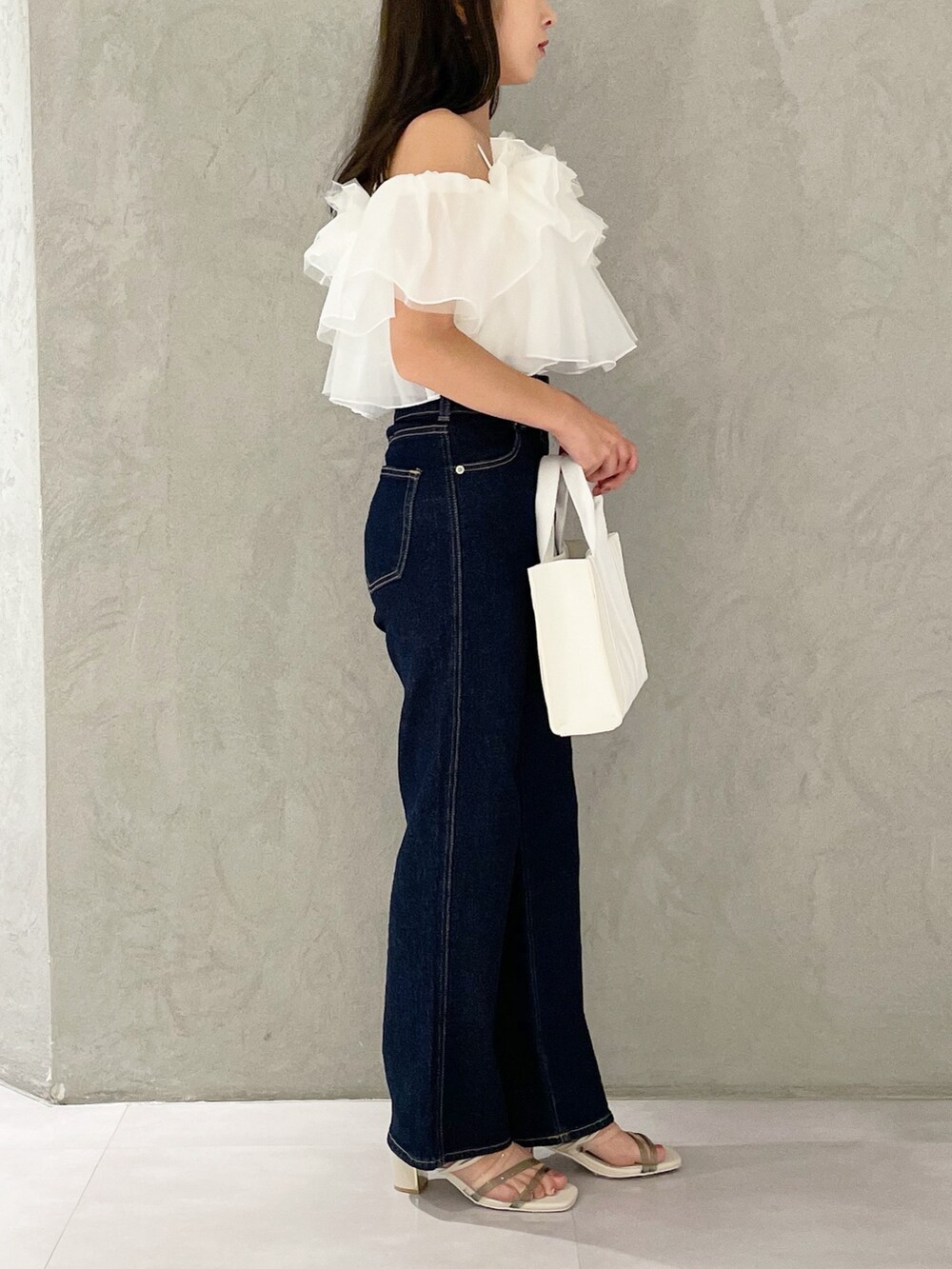 ピンク系のトートバッグ、ブルー系のデニムパンツ、ホワイト系のサンダルを着用したレディースの夏コーディネートの2枚目の写真