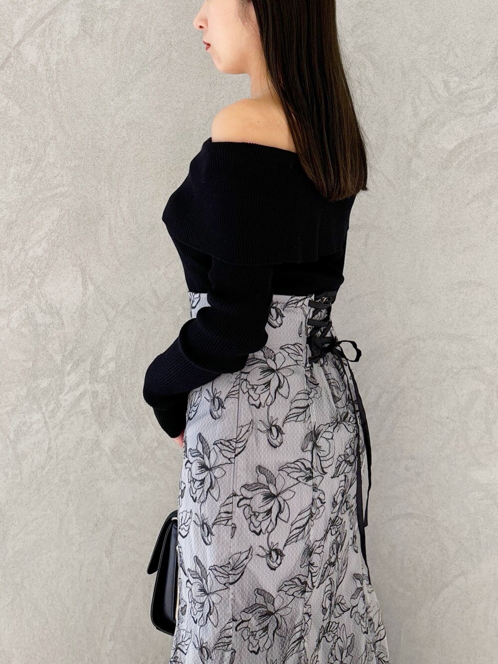 グレー系のスカート、ブラック系のブーツ、ブラック系のショルダーバッグを着用したレディースの秋コーディネートの3枚目の写真