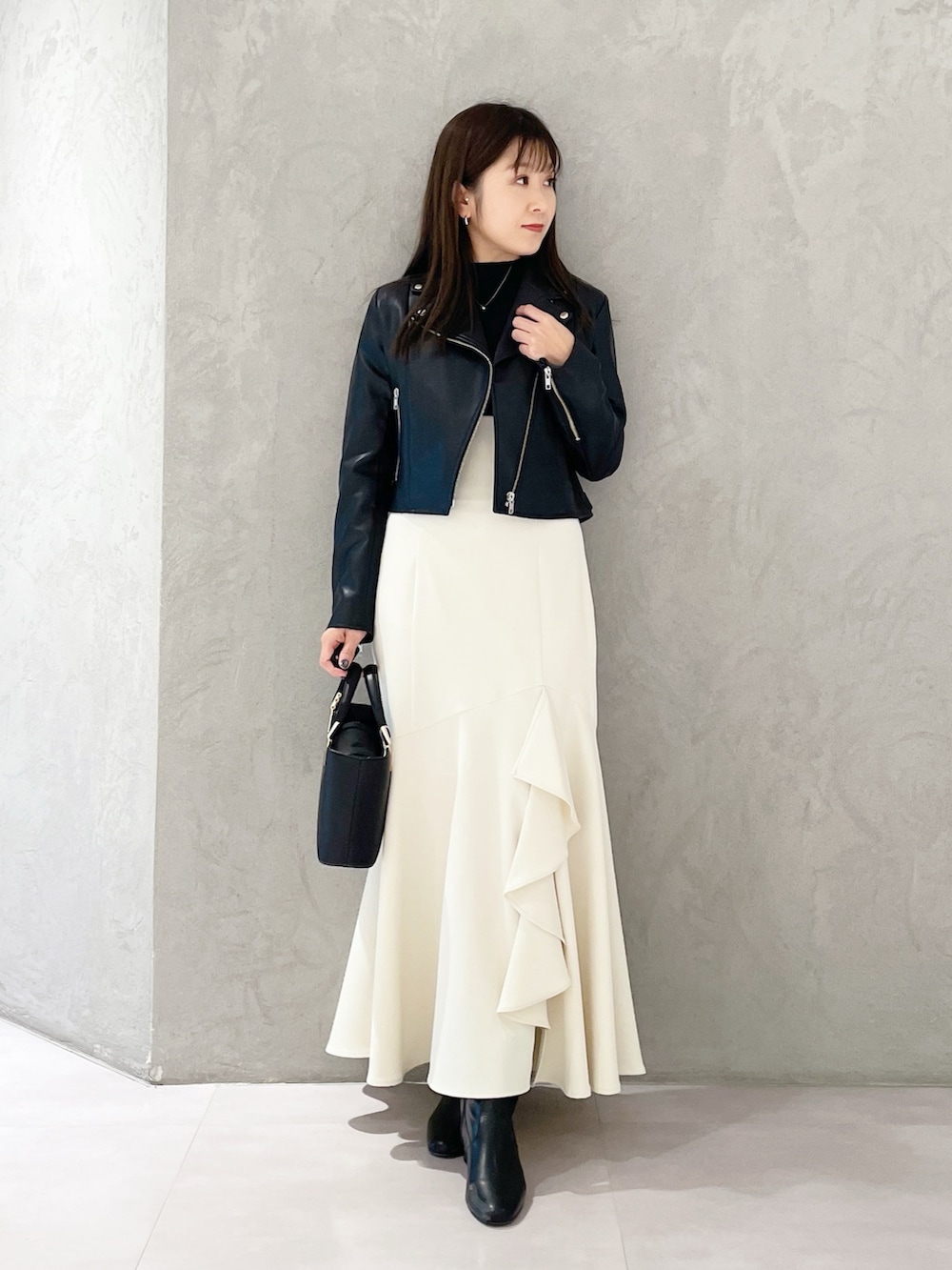 ブラック系のハンドバッグ、ブラック系のブーツ、ブラック系のライダースジャケットを着用したレディースの冬コーディネートの6枚目の写真