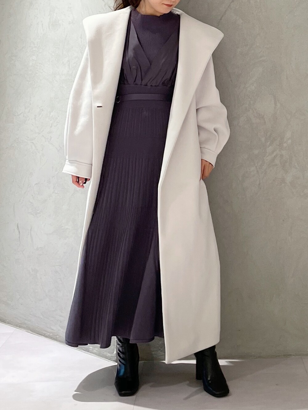 ホワイト系のチェスターコート、ブラック系のブーツ、ブルー系のワンピースを着用したレディースの秋コーディネートの3枚目の写真