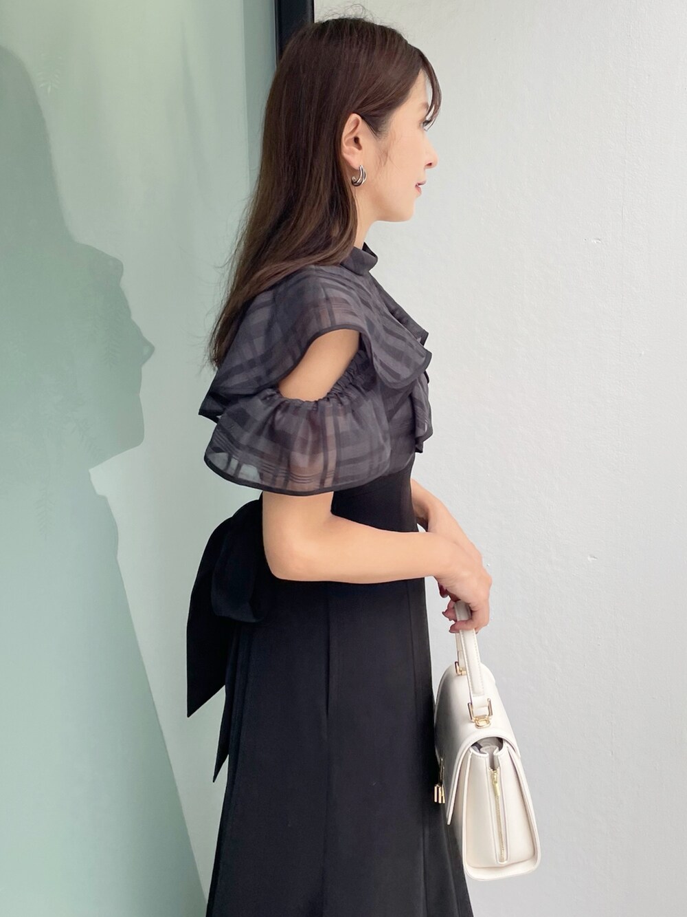 ブラック系のワンピース、ブラック系のサンダル、ホワイト系のショルダーバッグを着用したレディースの夏コーディネートの3枚目の写真