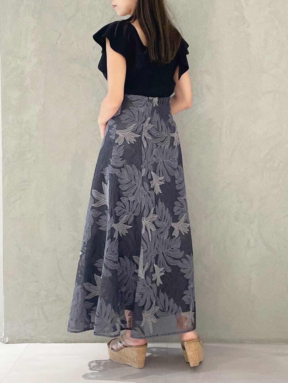 ブラック系のニット/セーター、ホワイト系のショルダーバッグ、ブラウン系のサンダルを着用したレディースの夏コーディネートの3枚目の写真