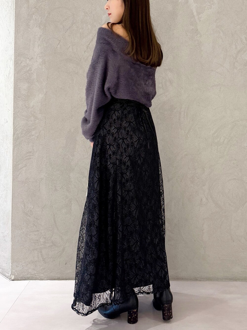 ブラック系のスカート、ブラック系のブーツ、ホワイト系のショルダーバッグを着用したレディースの冬コーディネートの2枚目の写真