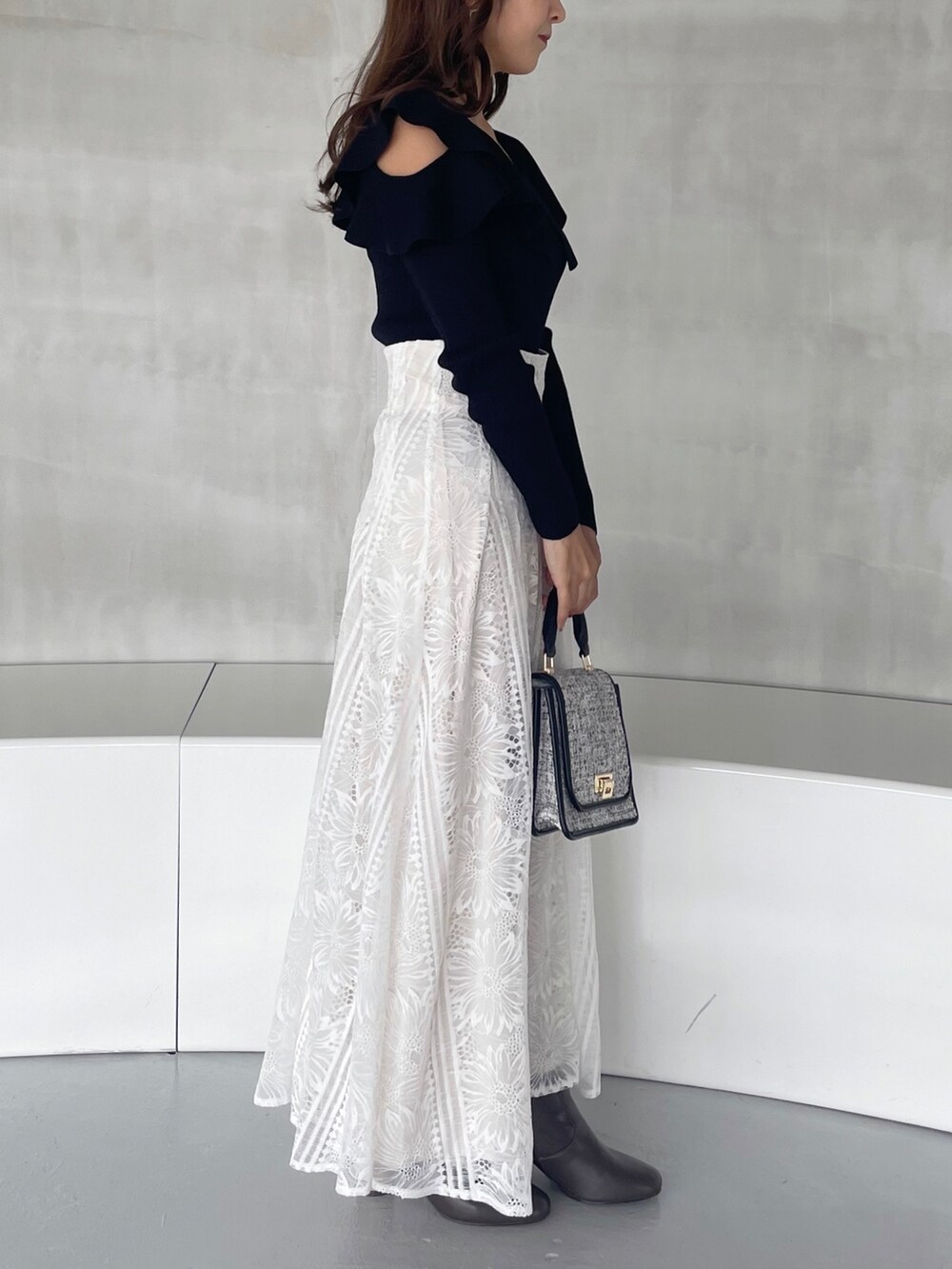 ホワイト系のスカート、ブラック系のショルダーバッグ、ブラウン系のブーツを着用したレディースの秋コーディネートの3枚目の写真