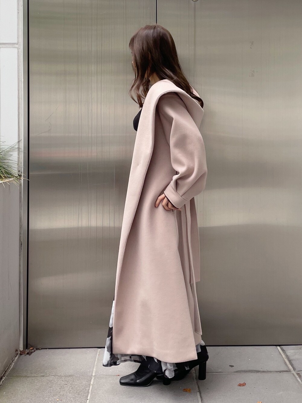 ブラック系のスカート、ブラック系のニット/セーター、ベージュ系のチェスターコートを着用したレディースの秋コーディネートの4枚目の写真