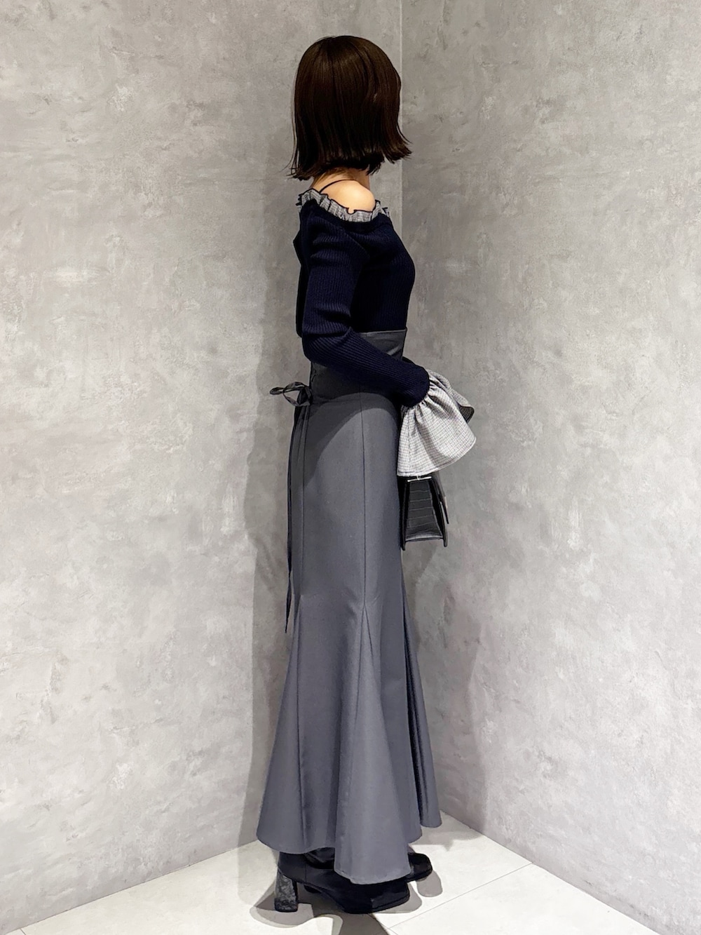 グレー系のスカート、ブラック系のハンドバッグ、ブルー系のニット/セーターを着用したレディースの冬コーディネートの3枚目の写真