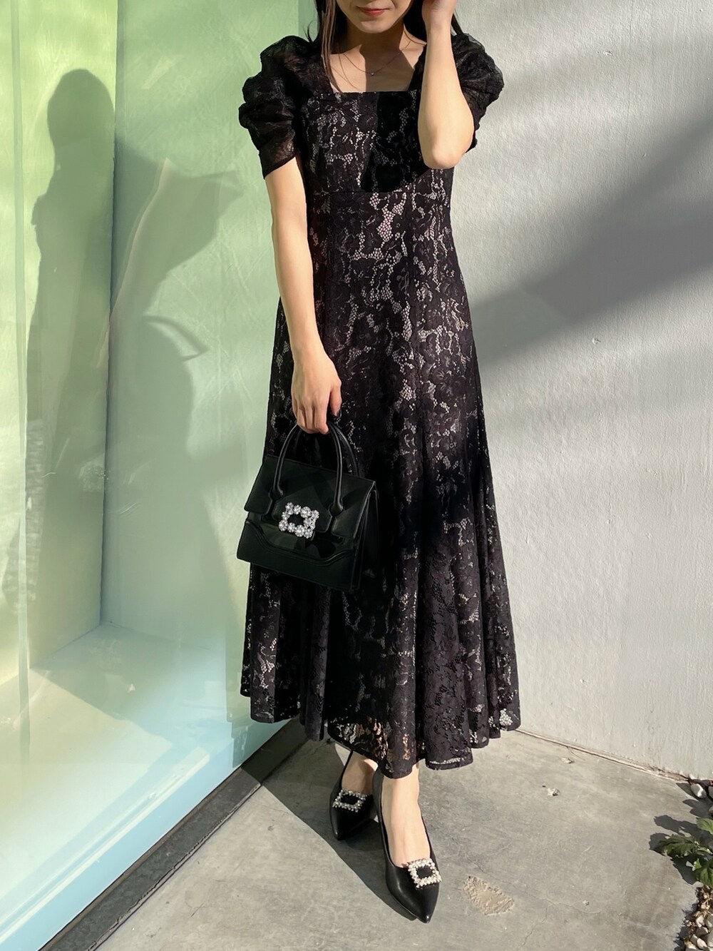 ブラック系のパンプス、ブラック系のショルダーバッグ、ブラック系のドレスを着用したレディースの春コーディネートの6枚目の写真