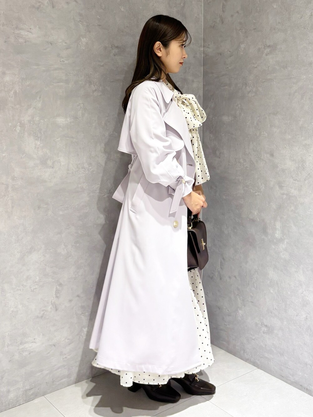 ホワイト系のワンピース、パープル系のトレンチコート、ブラウン系のハンドバッグを着用したレディースの冬コーディネートの7枚目の写真