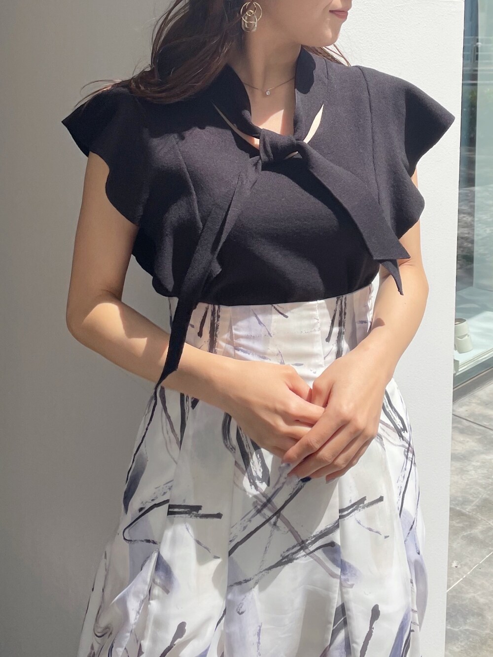 ブラック系のサンダル、ブラック系のニット/セーター、グレー系のスカートを着用したレディースの春コーディネートの2枚目の写真