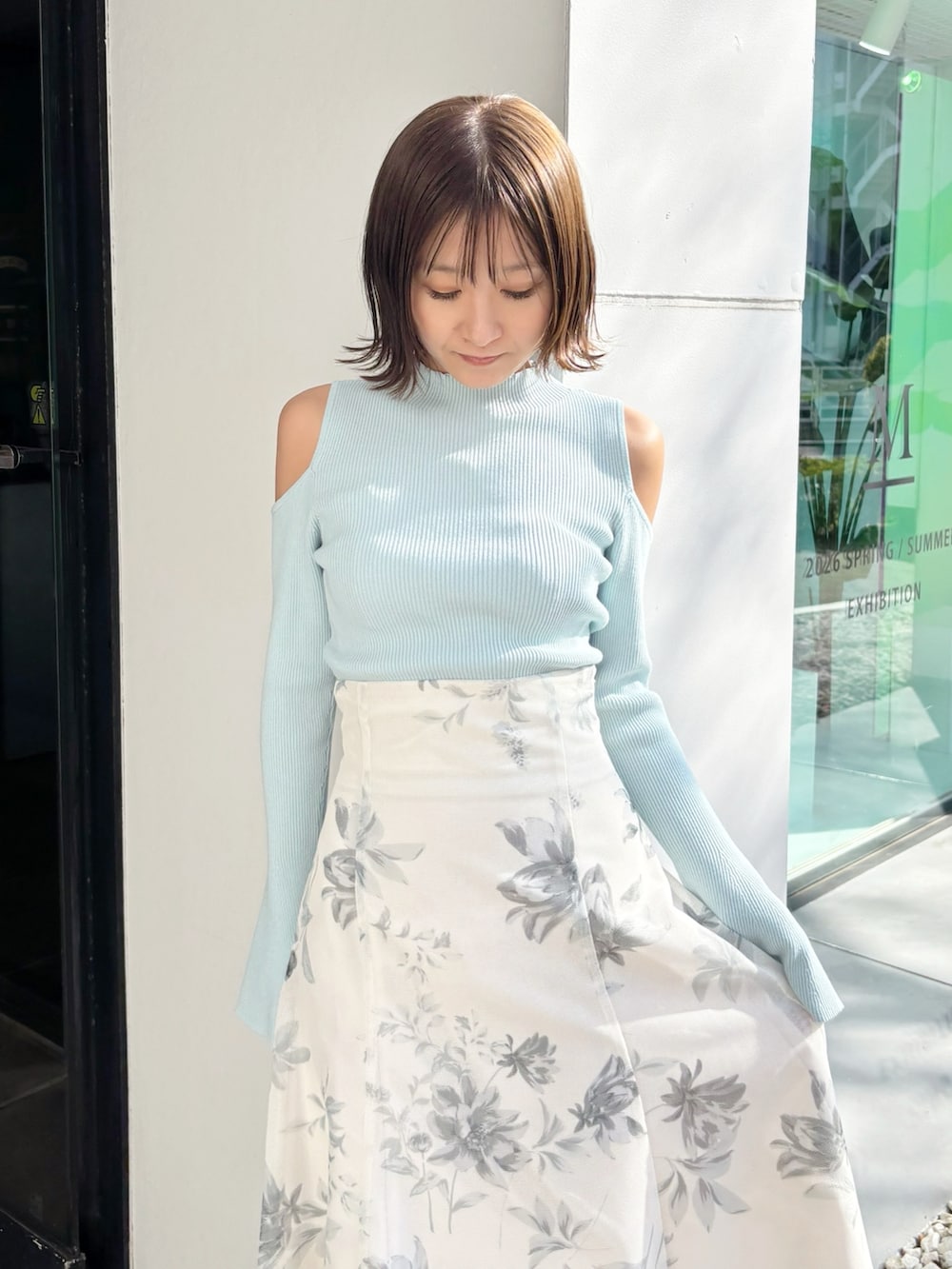 ホワイト系のスカート、グリーン系のニット/セーター、ホワイト系のパンプスを着用したレディースの春コーディネートの2枚目の写真