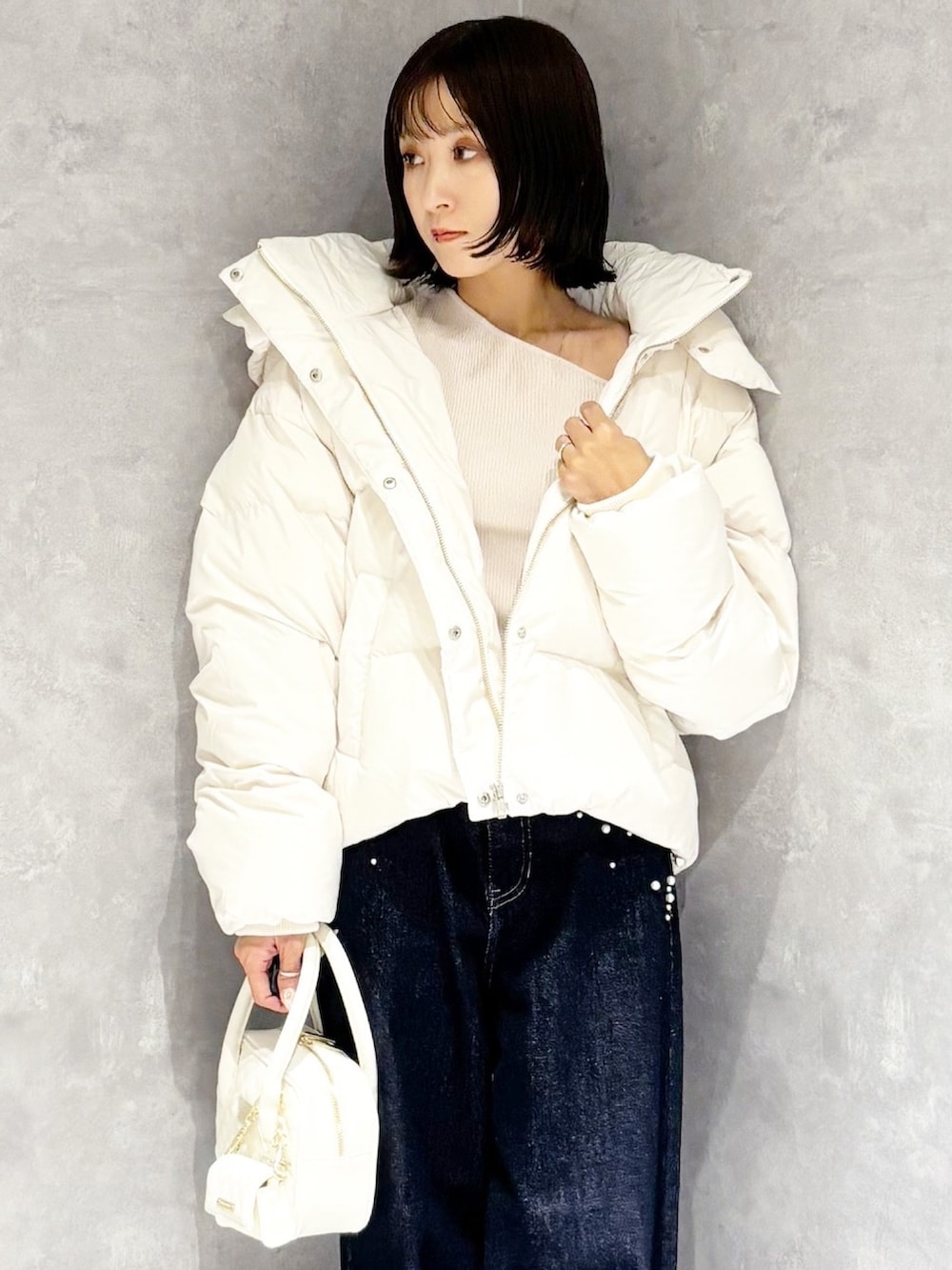 ブルー系のデニムパンツ、ホワイト系のダウンジャケット/コート、ベージュ系のニット/セーターを着用したレディースの秋コーディネートの4枚目の写真