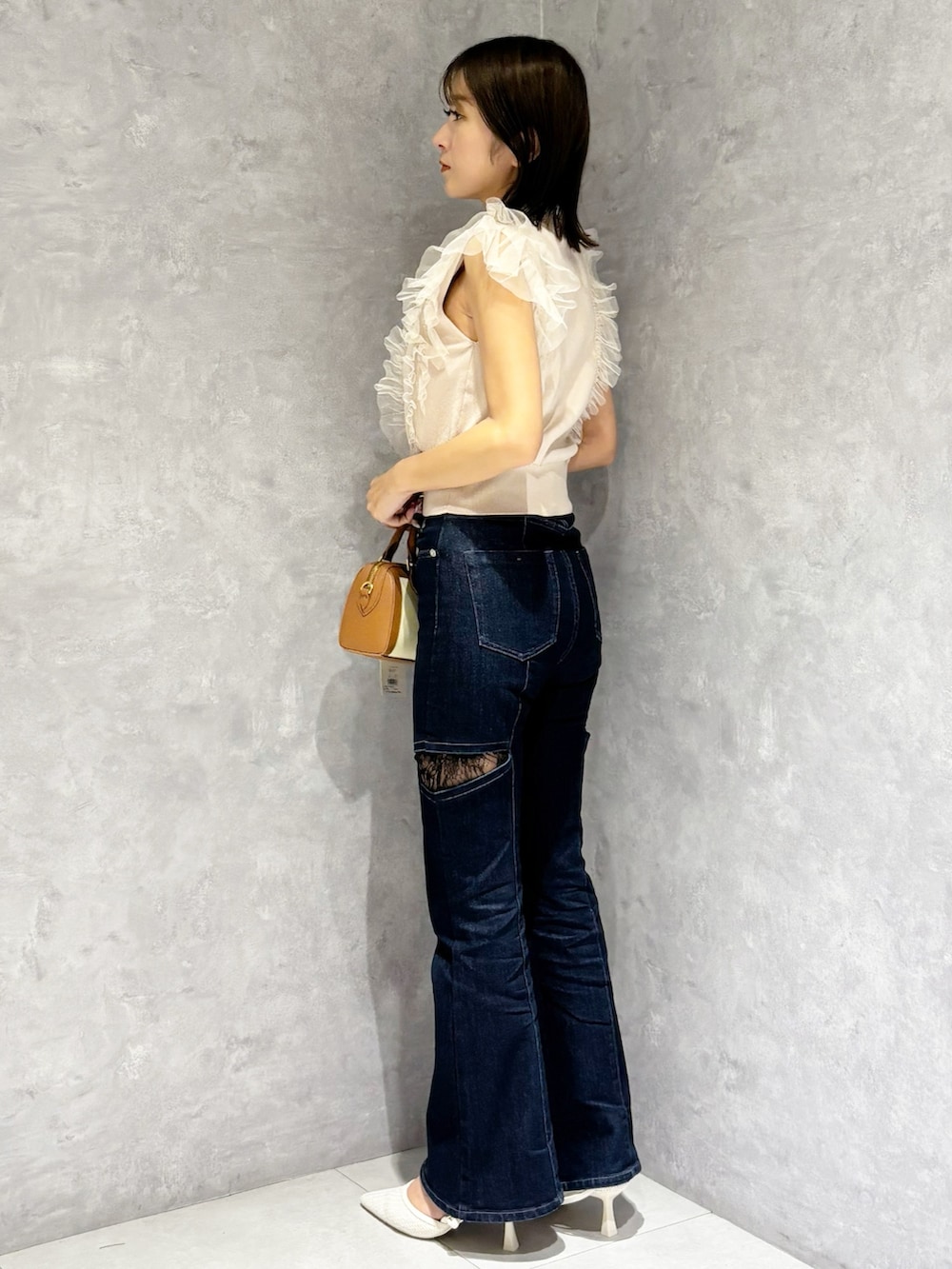 ブルー系のデニムパンツ、ピンク系のニット/セーター、ホワイト系のパンプスを着用したレディースの春コーディネートの2枚目の写真