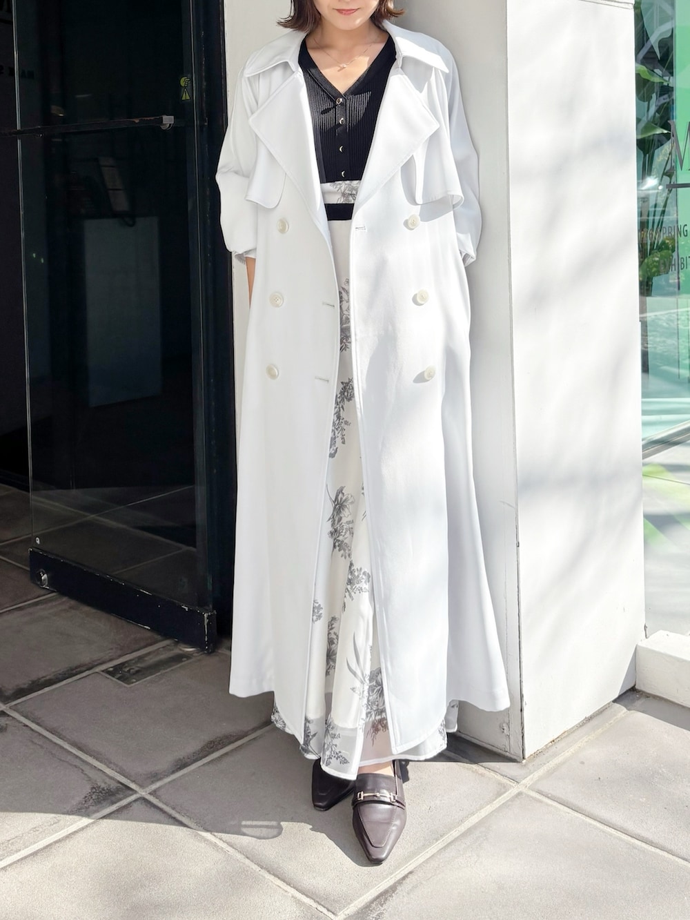 ブラック系のワンピース、ブラウン系のパンプス、ブルー系のトレンチコートを着用したレディースの春コーディネートの7枚目の写真