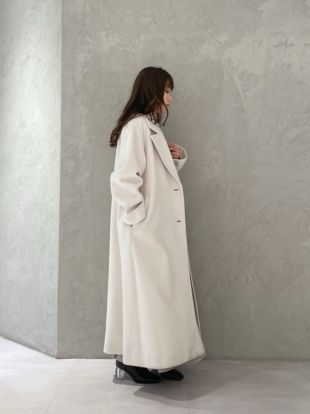 ベージュ系のワンピース、ホワイト系のチェスターコート、ブラック系のブーツを着用したレディースの冬コーディネートの3枚目の写真