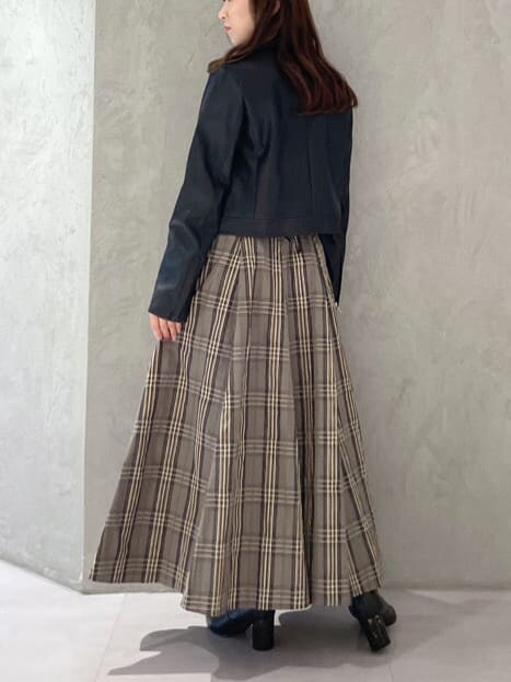 ブラック系のライダースジャケット、ブラック系のニット/セーター、ベージュ系のスカートを着用したレディースの秋コーディネートの4枚目の写真