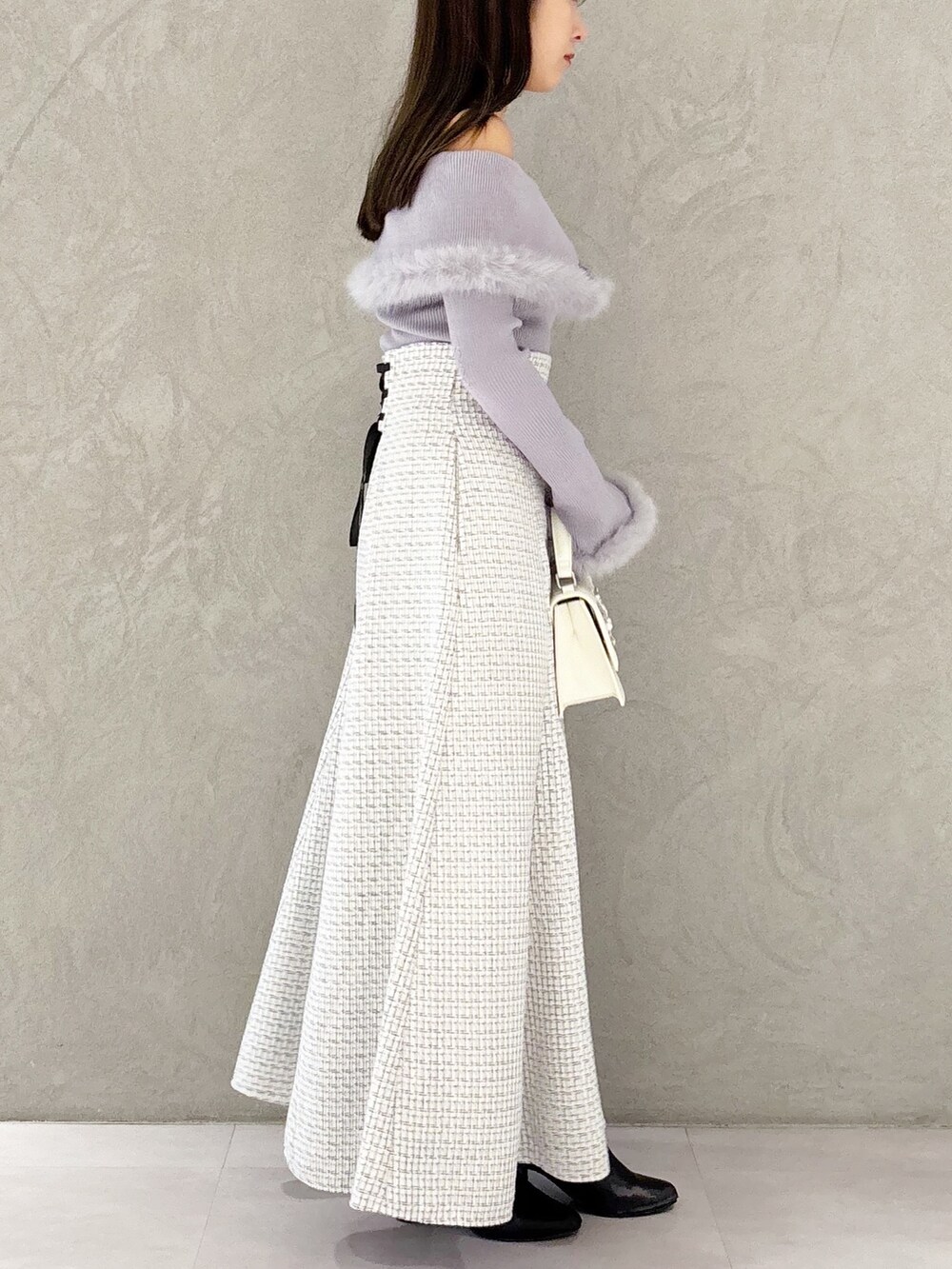 ホワイト系のスカート、ブラック系のブーツ、ホワイト系のショルダーバッグを着用したレディースの冬コーディネートの2枚目の写真