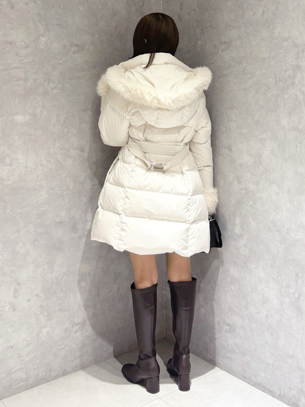 グレー系のスカート、ブラック系のニット/セーター、ホワイト系のダウンジャケット/コートを着用したレディースの冬コーディネートの3枚目の写真