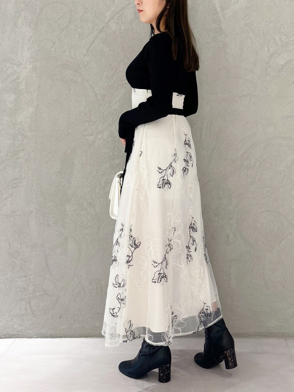 ホワイト系のワンピース、ブラック系のブーツ、ホワイト系のハンドバッグを着用したレディースの秋コーディネートの4枚目の写真