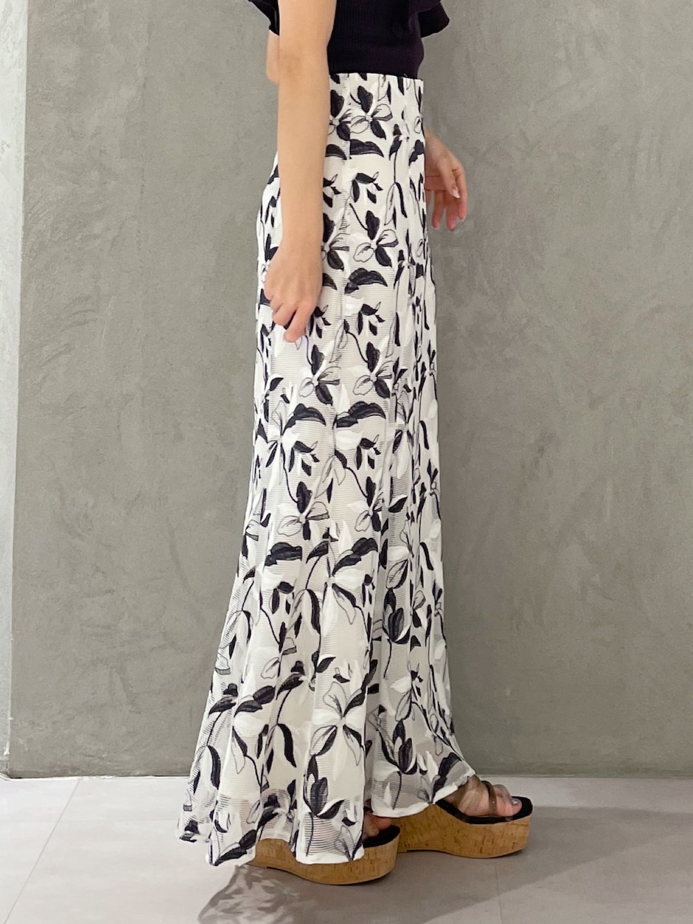 ホワイト系のスカート、グレー系のニット/セーター、ブラック系のサンダルを着用したレディースの春コーディネートの2枚目の写真