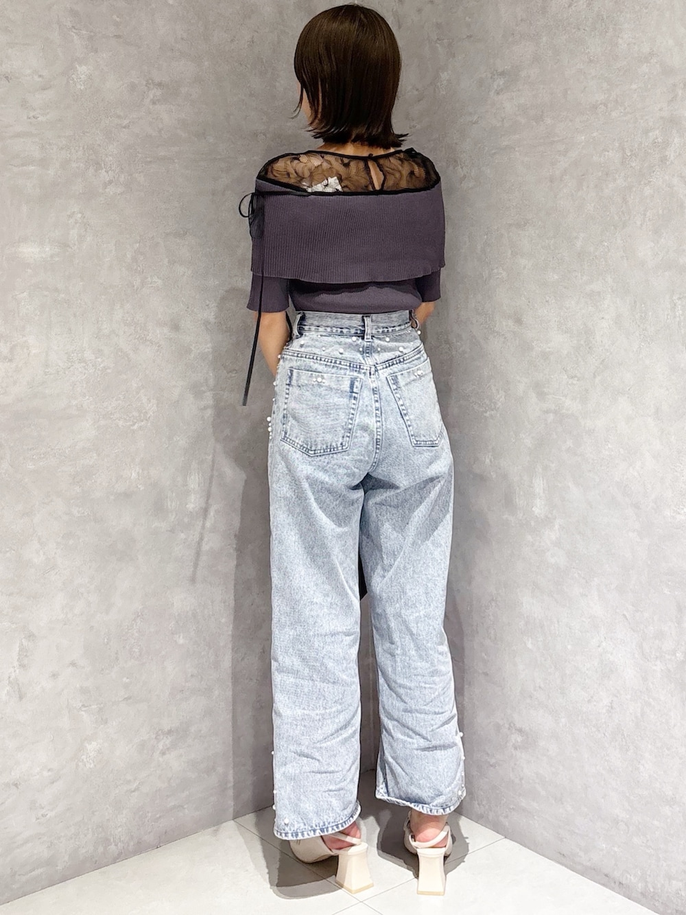 ブルー系のデニムパンツ、ホワイト系のパンプス、グレー系のニット/セーターを着用したレディースの春コーディネートの3枚目の写真