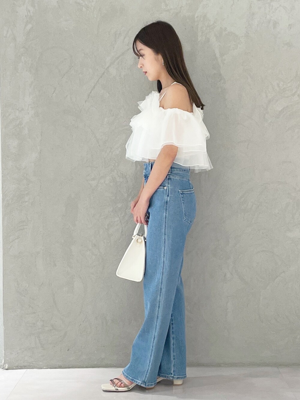 ブルー系のデニムパンツ、ホワイト系のショルダーバッグ、ホワイト系のサンダルを着用したレディースの夏コーディネートの2枚目の写真