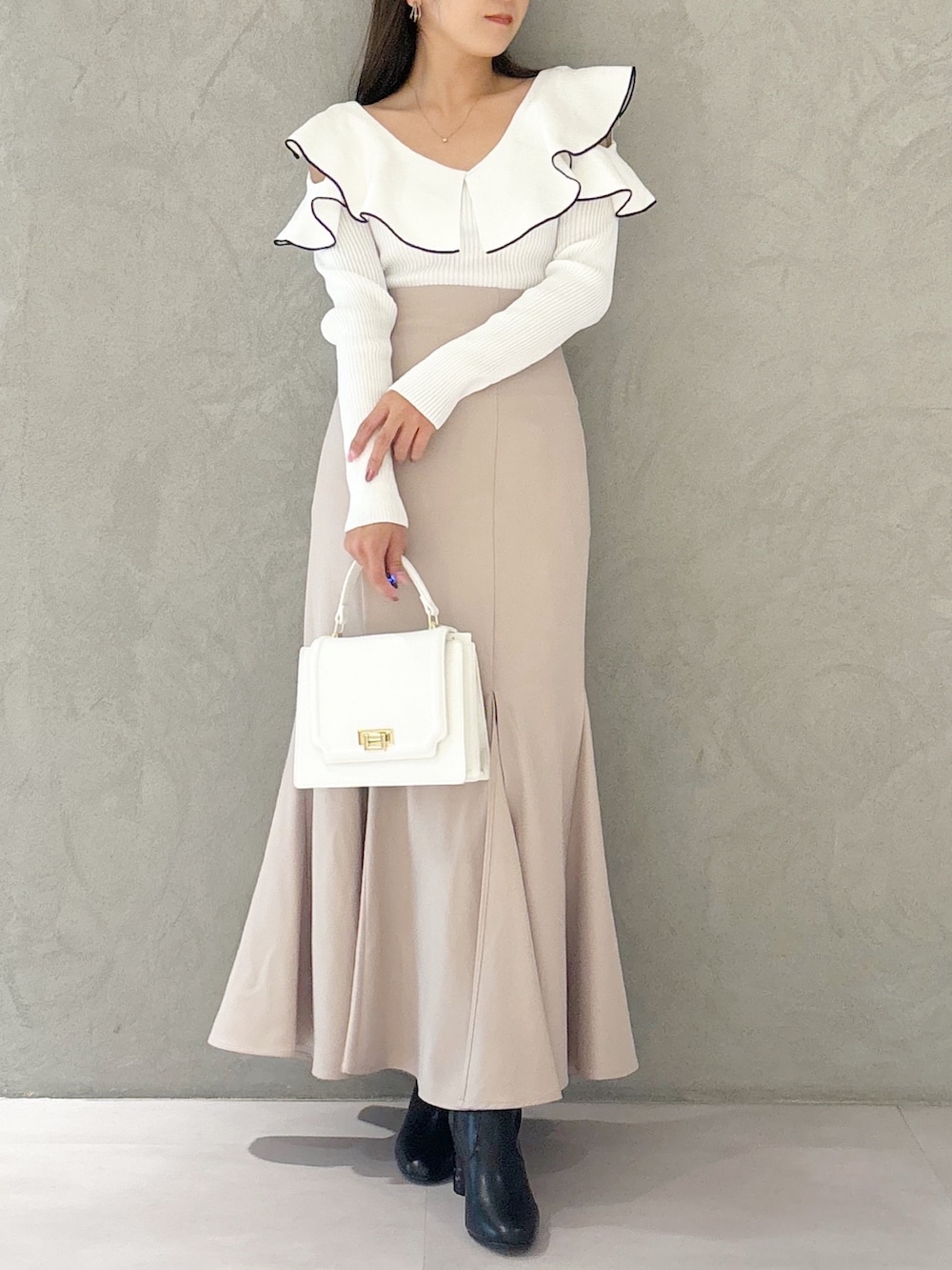 ピンク系のスカート、ブラック系のブーツ、ホワイト系のハンドバッグを着用したレディースの秋コーディネートの3枚目の写真