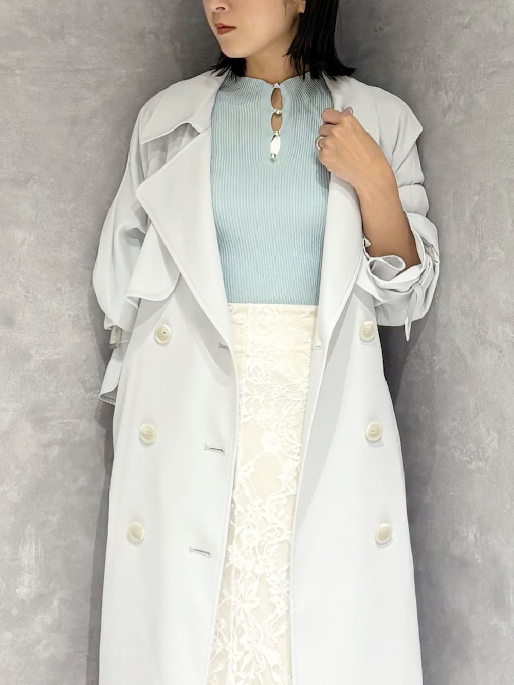 ホワイト系のスカート、ブルー系のトレンチコート、グリーン系のニット/セーターを着用したレディースの春コーディネートの5枚目の写真