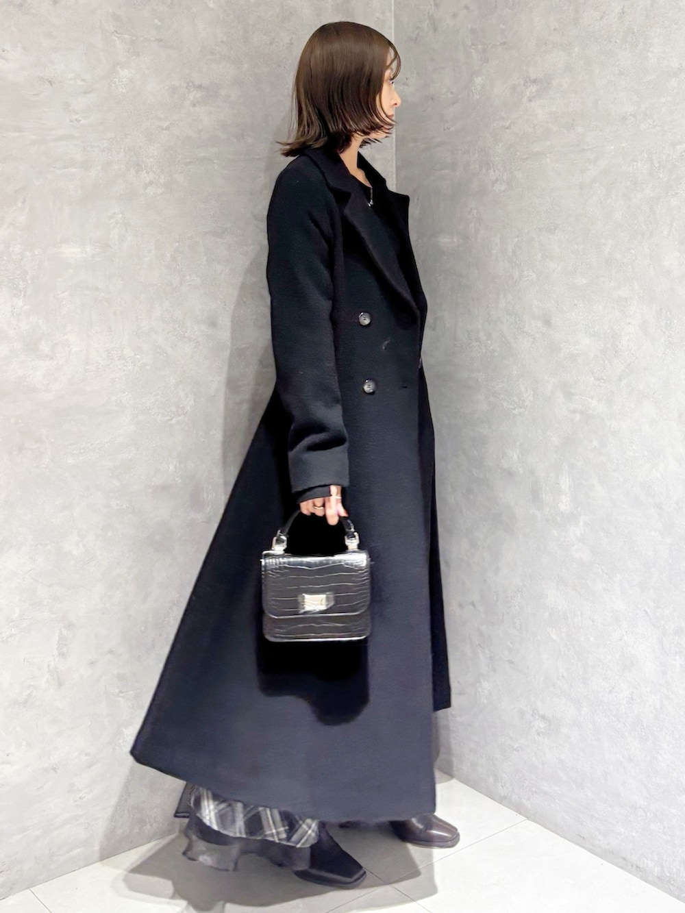 ブラック系のスカート、ブラック系のニット/セーター、ブラック系のその他アウターを着用したレディースの冬コーディネートの2枚目の写真