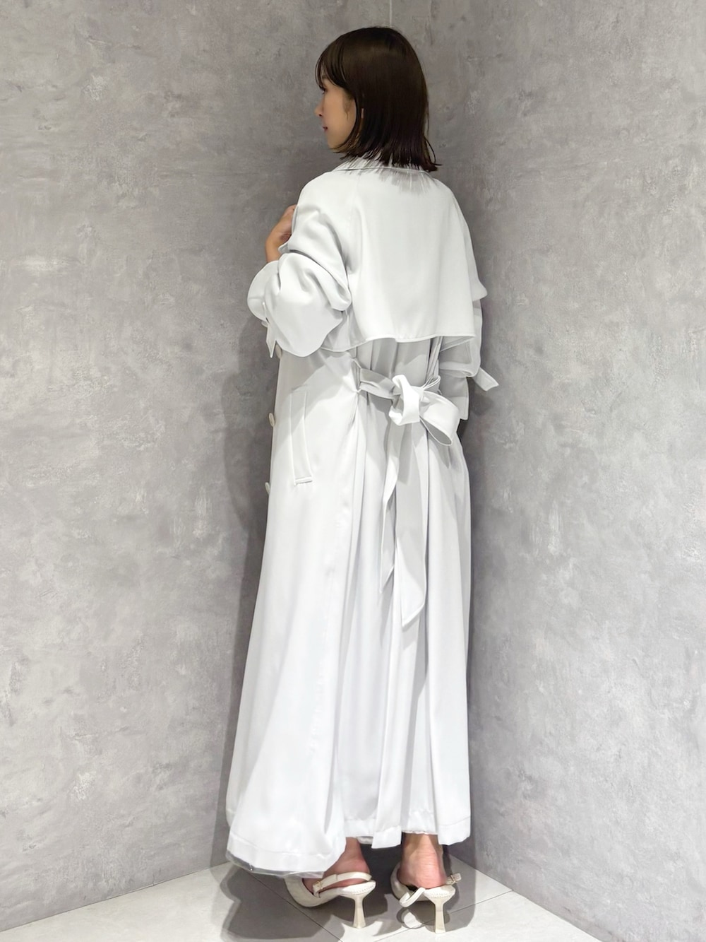 ホワイト系のスカート、ブルー系のトレンチコート、グリーン系のニット/セーターを着用したレディースの春コーディネートの4枚目の写真