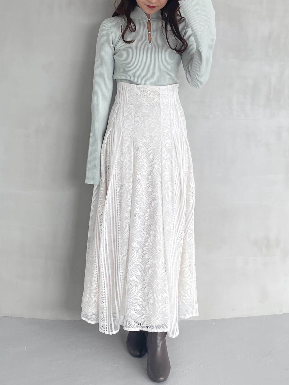 ホワイト系のスカート、グリーン系のニット/セーター、ブラウン系のブーツを着用したレディースの秋コーディネートの4枚目の写真