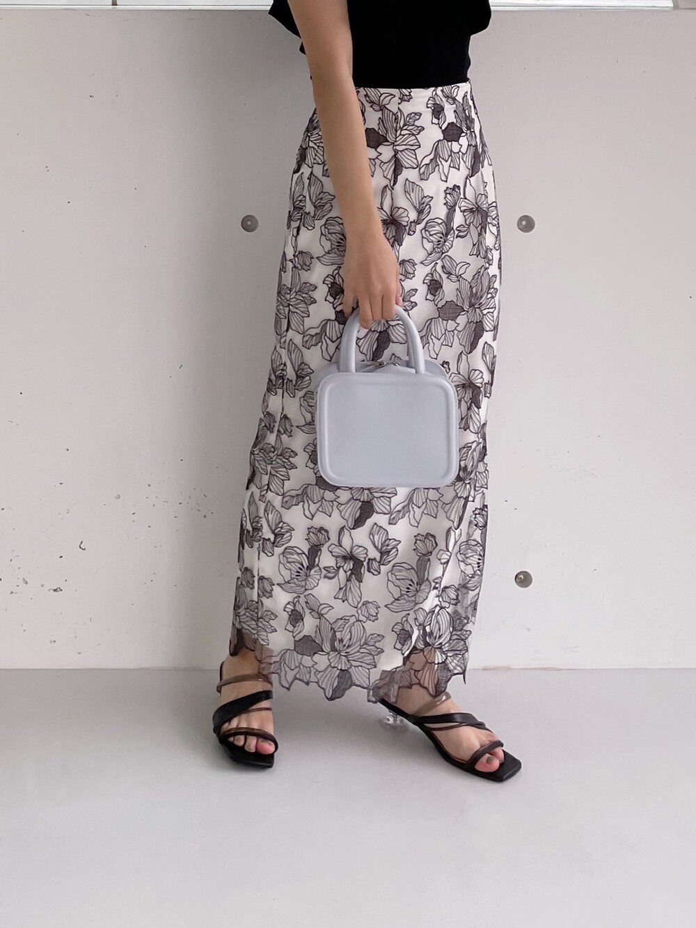 ホワイト系のスカート、ブラック系のニット/セーター、ブラック系のサンダルを着用したレディースの冬コーディネートの4枚目の写真