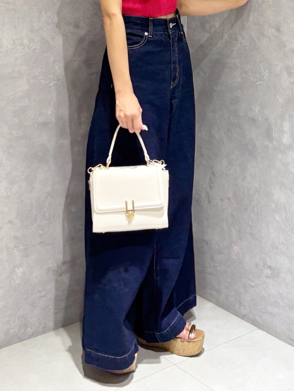 ブルー系のデニムパンツ、ブラウン系のサンダル、ホワイト系のハンドバッグを着用したレディースの夏コーディネートの4枚目の写真