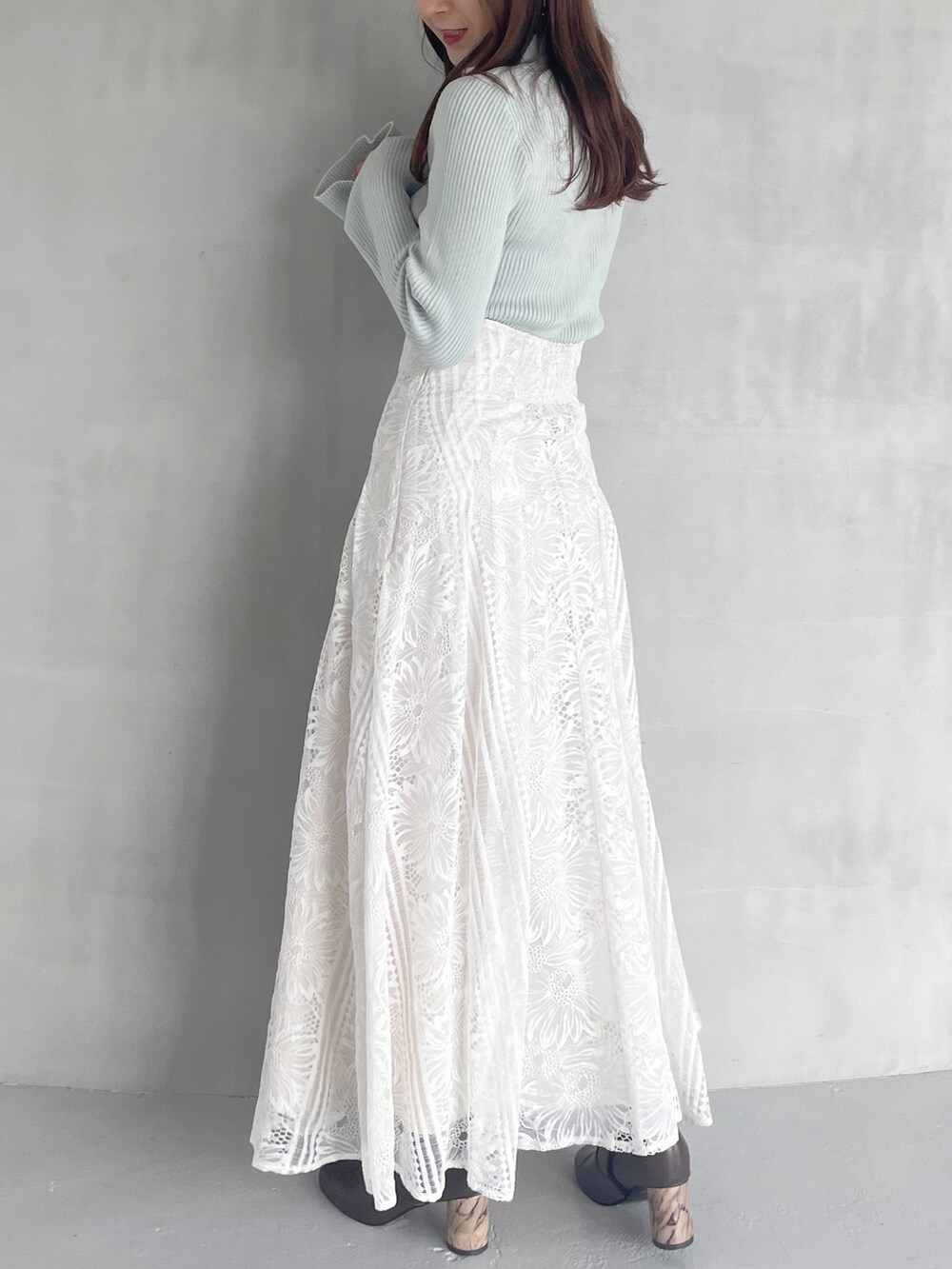 ホワイト系のスカート、グリーン系のニット/セーター、ブラウン系のブーツを着用したレディースの秋コーディネートの2枚目の写真