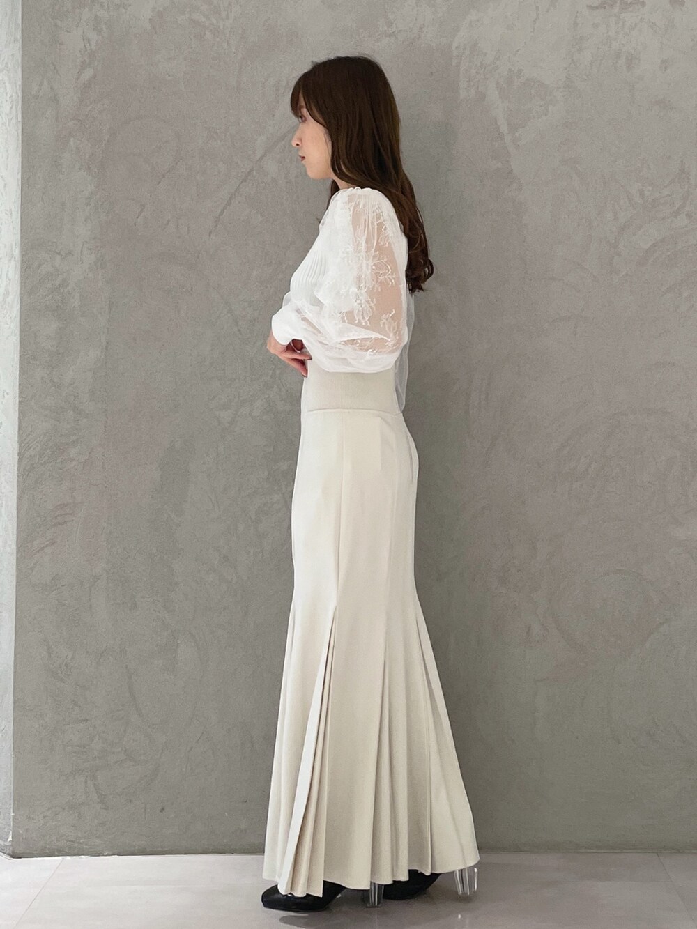 ホワイト系のスカート、ホワイト系のカーディガン/ボレロ、ブラック系のブーツを着用したレディースの冬コーディネートの2枚目の写真