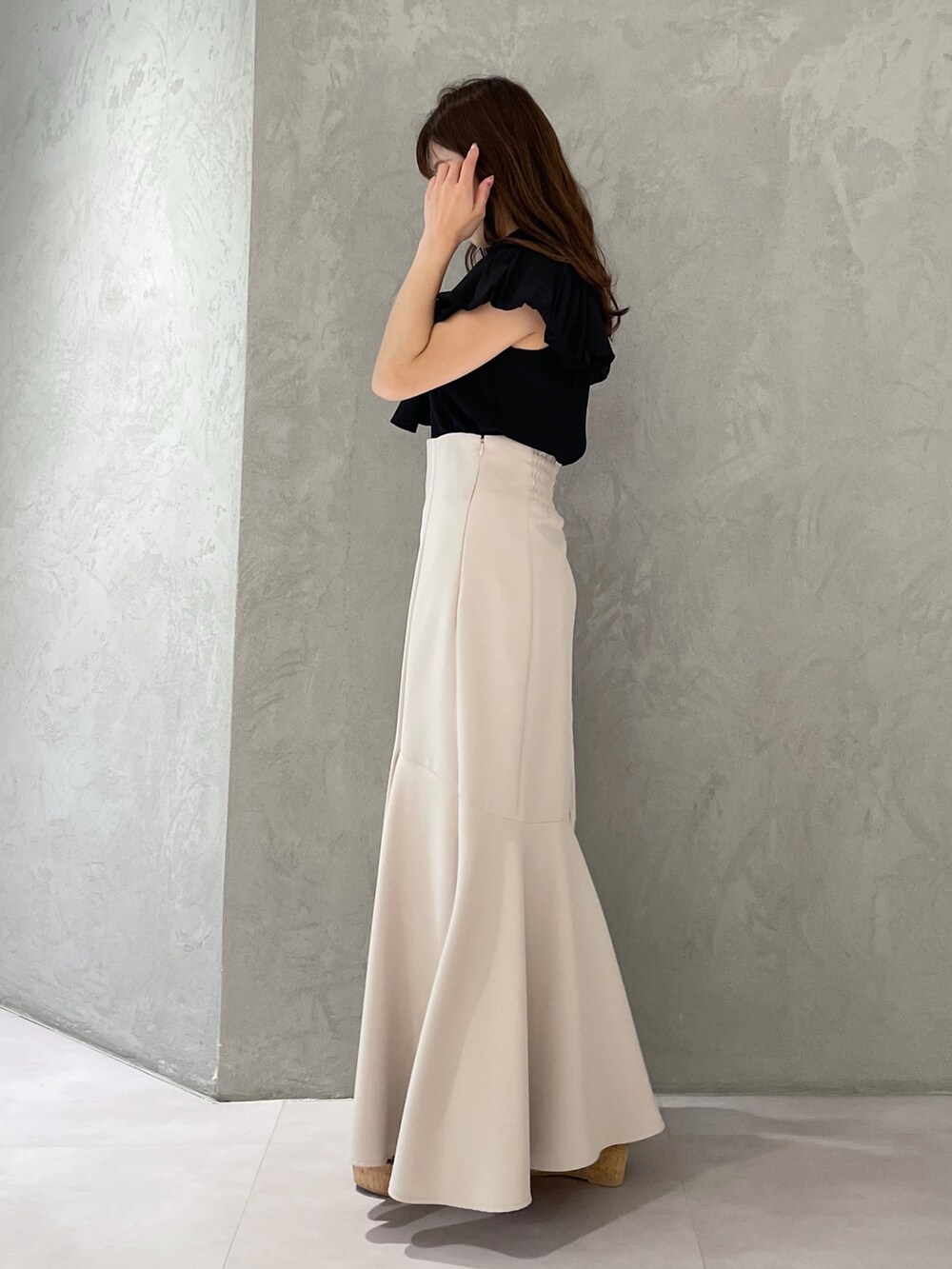 グレー系のハンドバッグ、ベージュ系のスカート、ブラック系のサンダルを着用したレディースの春コーディネートの5枚目の写真