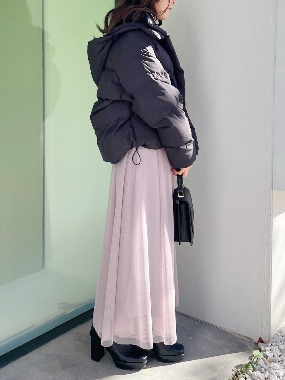 グレー系のワンピース、ブラック系のダウンジャケット/コート、ブラック系のハンドバッグを着用したレディースの冬コーディネートの3枚目の写真