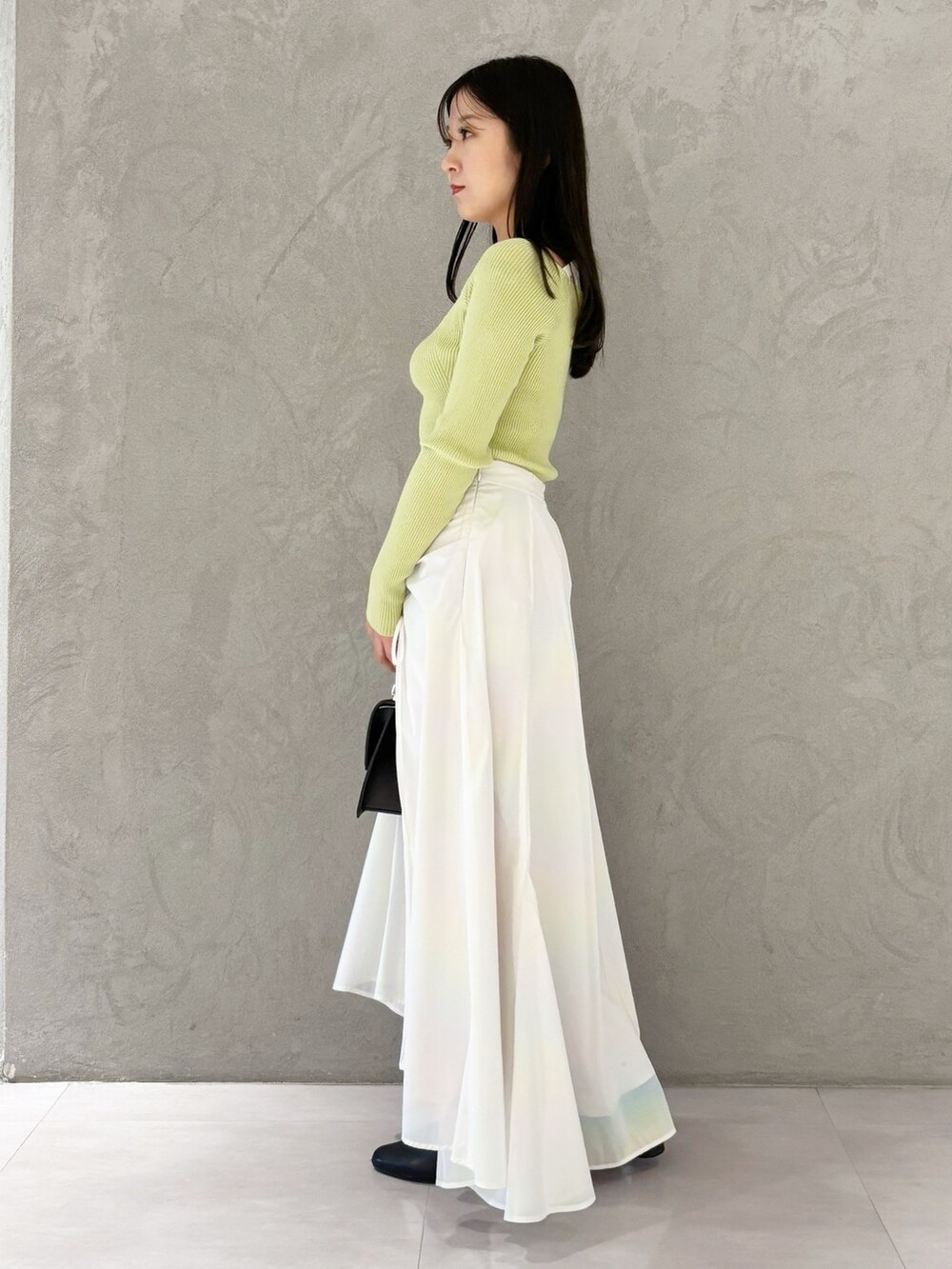 ホワイト系のスカート、ブラック系のブーツ、ブラウン系のハンドバッグを着用したレディースの冬コーディネートの6枚目の写真