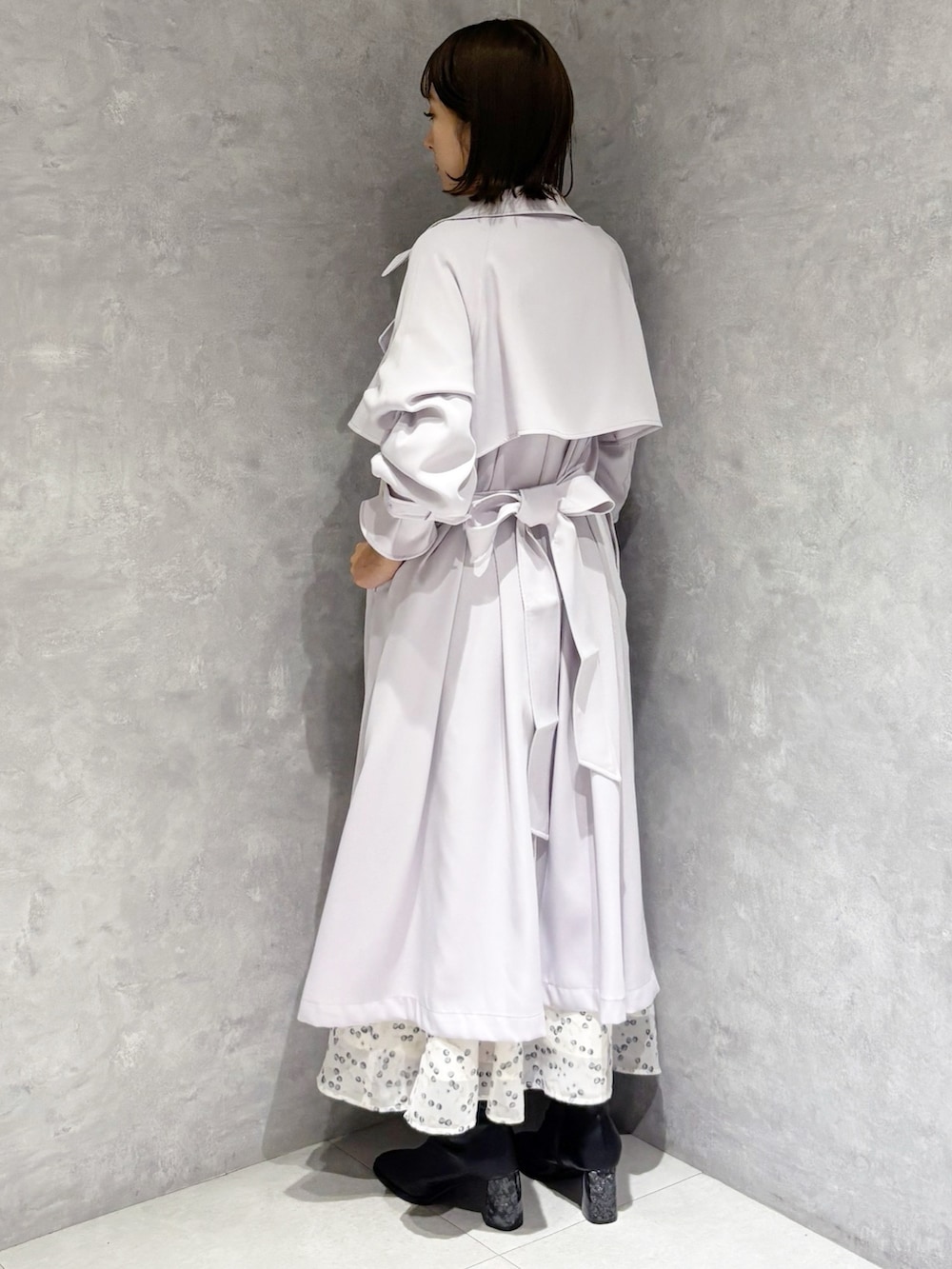 ホワイト系のワンピース、ブラック系のブーツ、パープル系のトレンチコートを着用したレディースの冬コーディネートの3枚目の写真