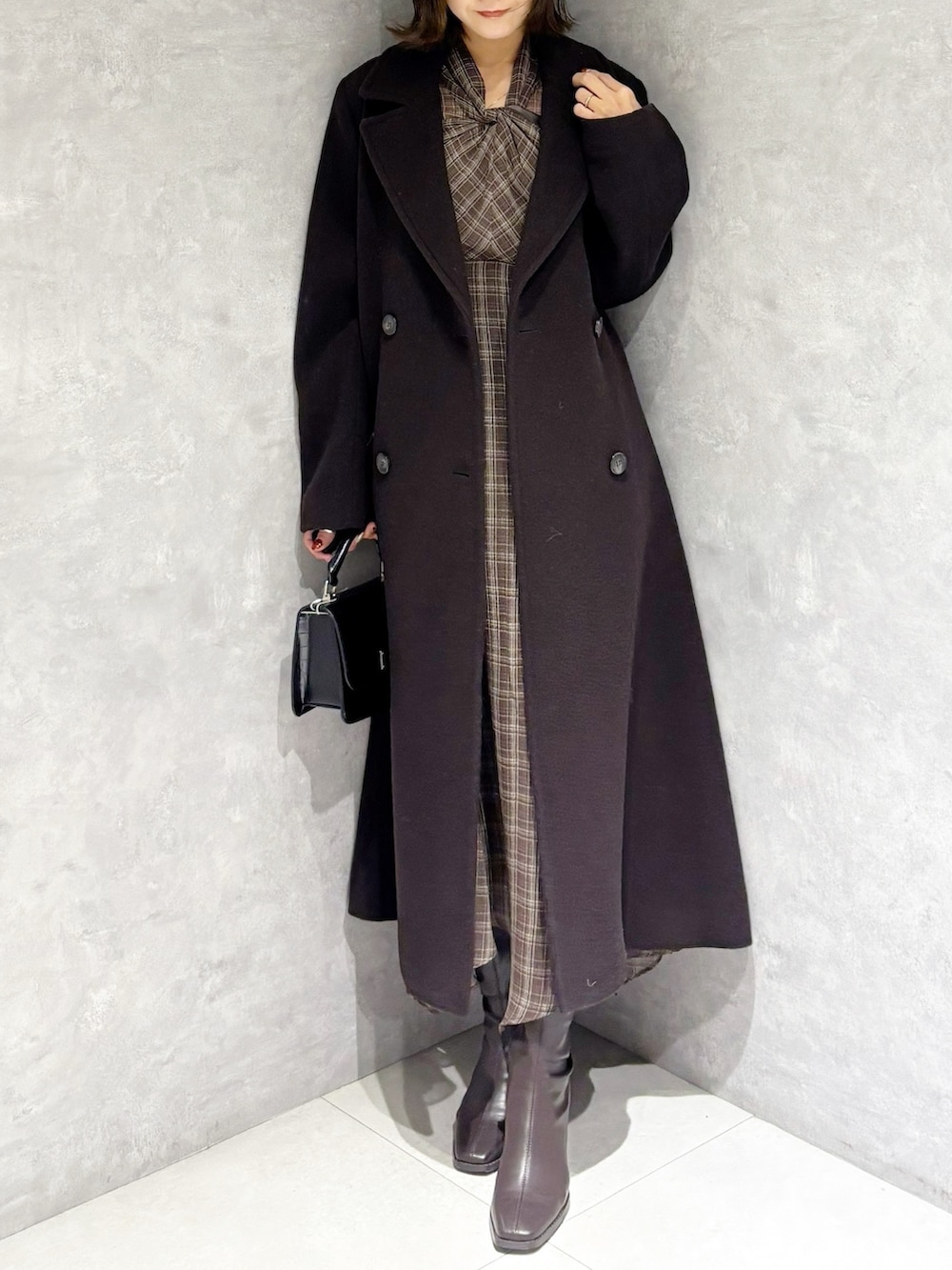 ブラウン系のチェスターコート、ブラウン系のワンピース、ブラウン系のブーツを着用したレディースの冬コーディネートの5枚目の写真