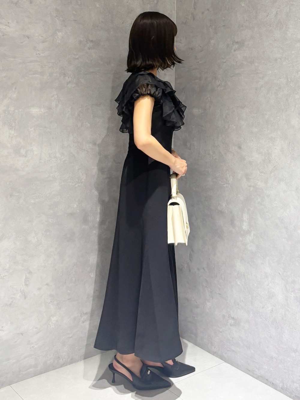 ブラック系のワンピース、ブラック系のパンプス、ホワイト系のハンドバッグを着用したレディースの夏コーディネートの3枚目の写真