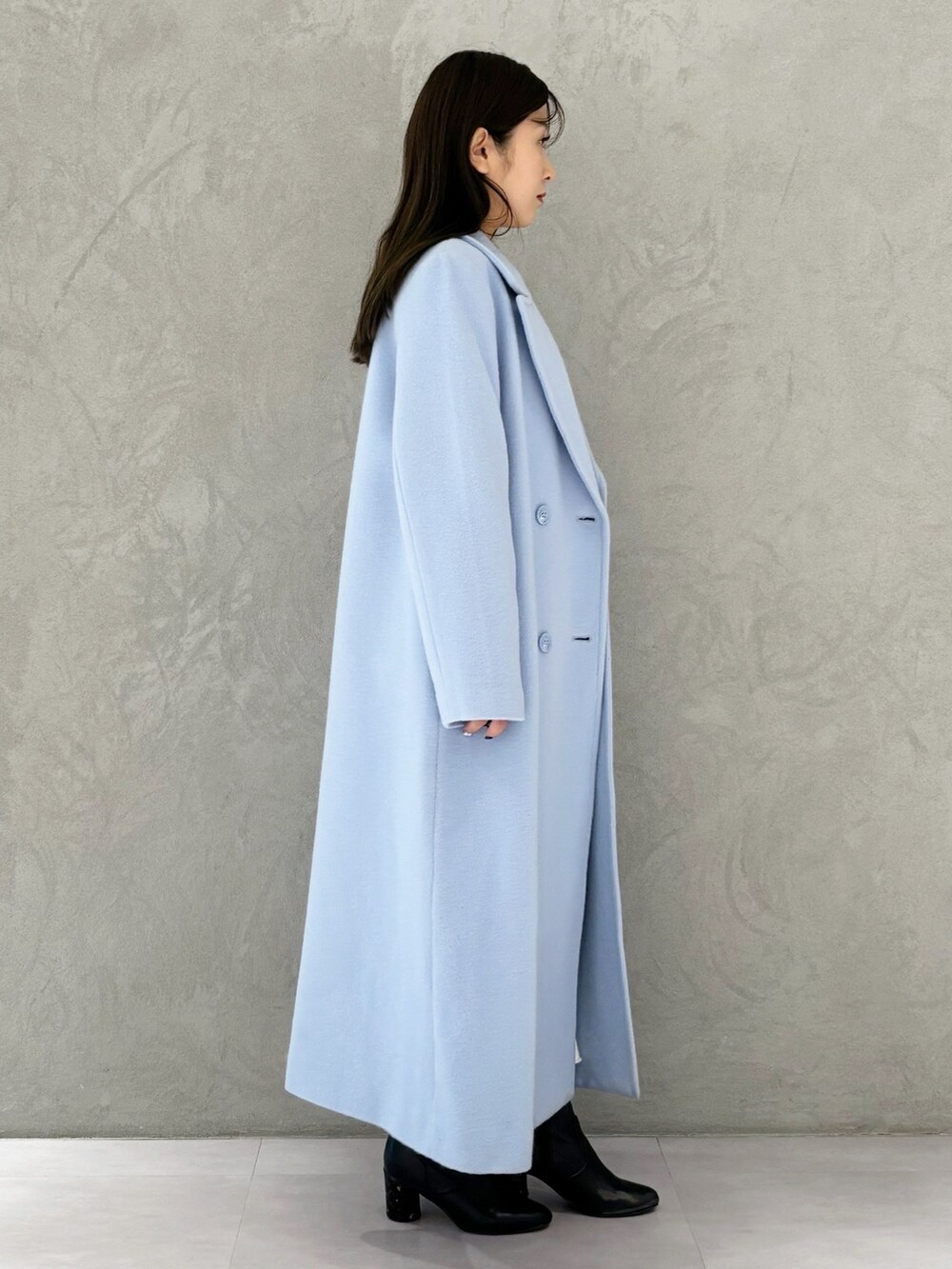 ブルー系のチェスターコート、ブラック系のブーツ、ホワイト系のワンピースを着用したレディースの冬コーディネートの4枚目の写真