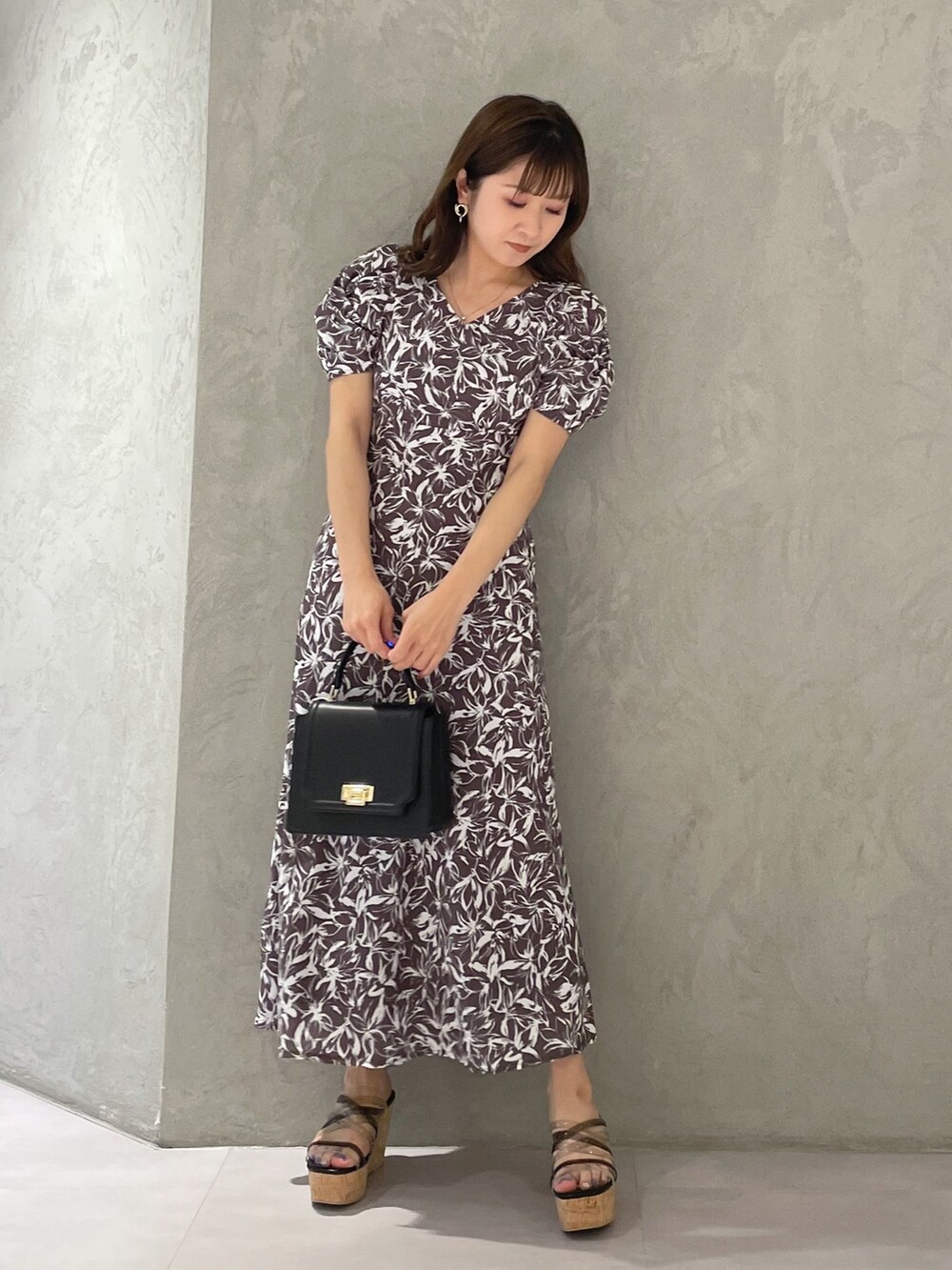 ブラック系のサンダル、ブラック系のハンドバッグ、グレー系のワンピースを着用したレディースの春コーディネートの2枚目の写真
