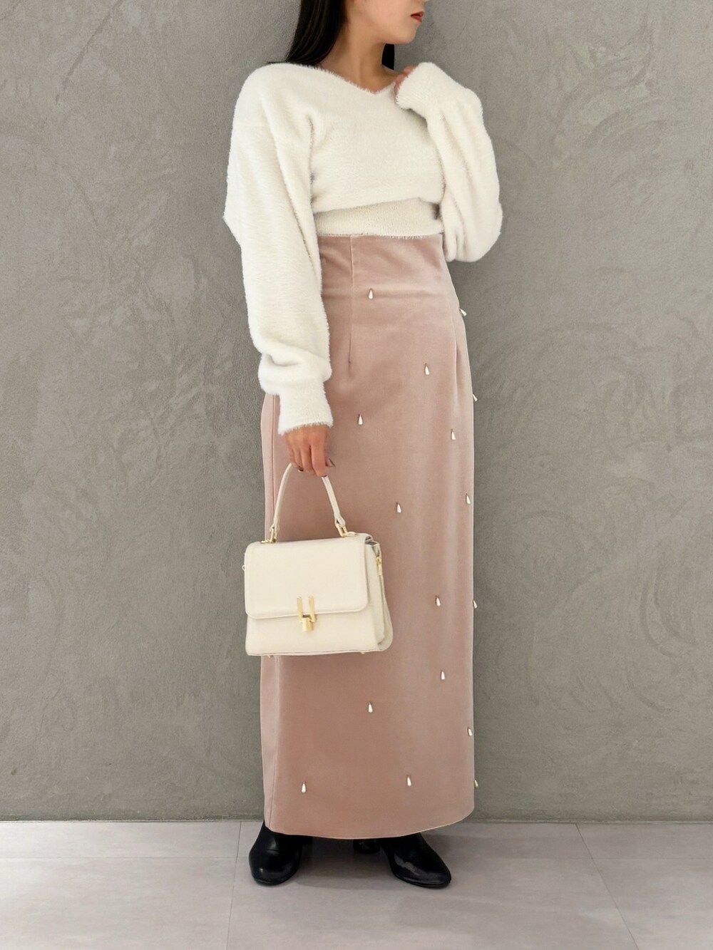 ピンク系のスカート、ブラック系のブーツ、ホワイト系のニット/セーターを着用したレディースの冬コーディネートの3枚目の写真