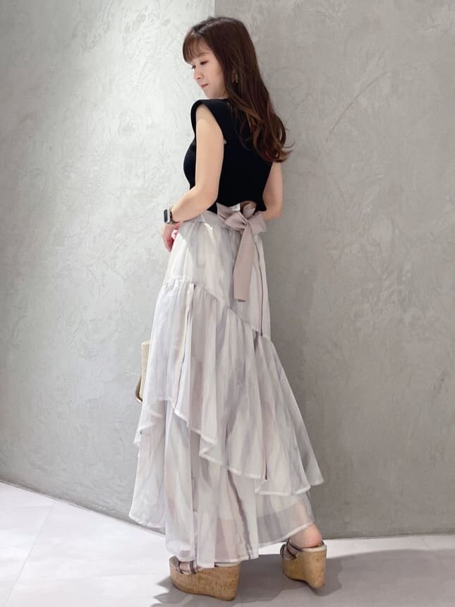 ピンク系のスカート、ブラック系のニット/セーター、ベージュ系のトートバッグを着用したレディースの夏コーディネートの4枚目の写真