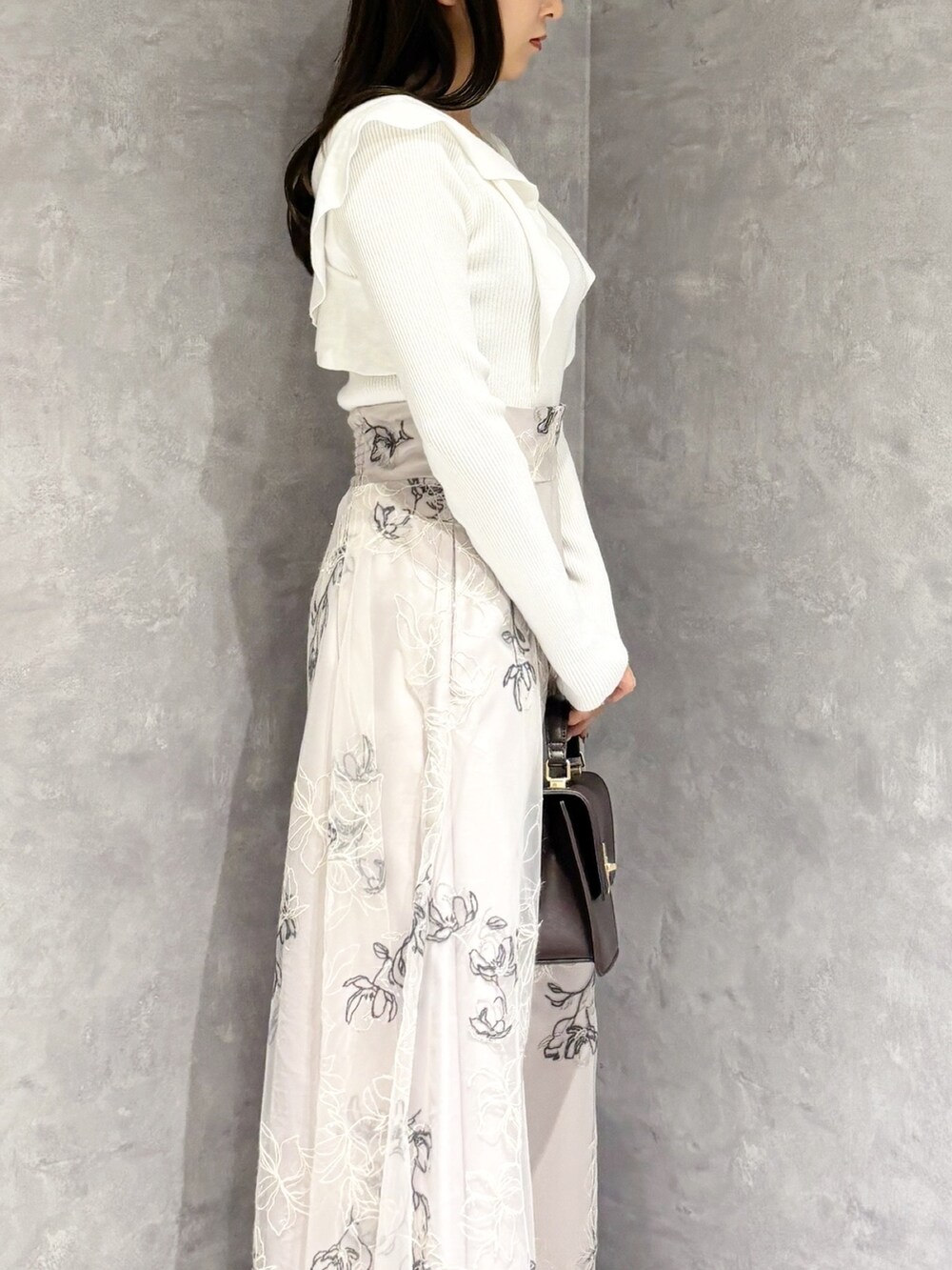 ブラウン系のハンドバッグ、ブラック系のブーツ、ベージュ系のスカートを着用したレディースの冬コーディネートの4枚目の写真