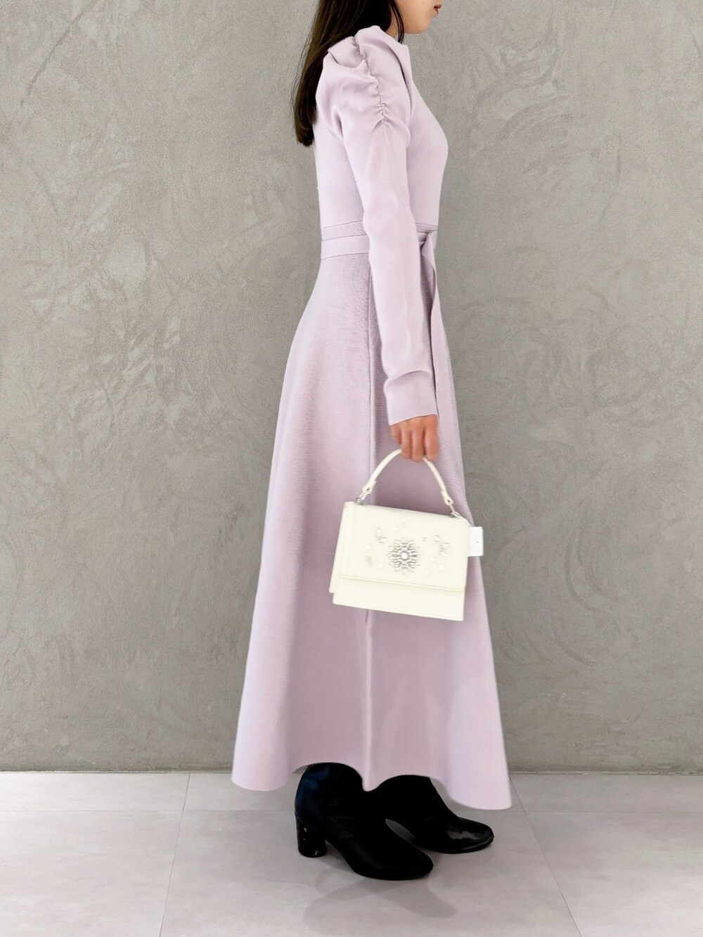 ホワイト系のショルダーバッグ、ブラック系のブーツ、パープル系のワンピースを着用したレディースの冬コーディネートの7枚目の写真