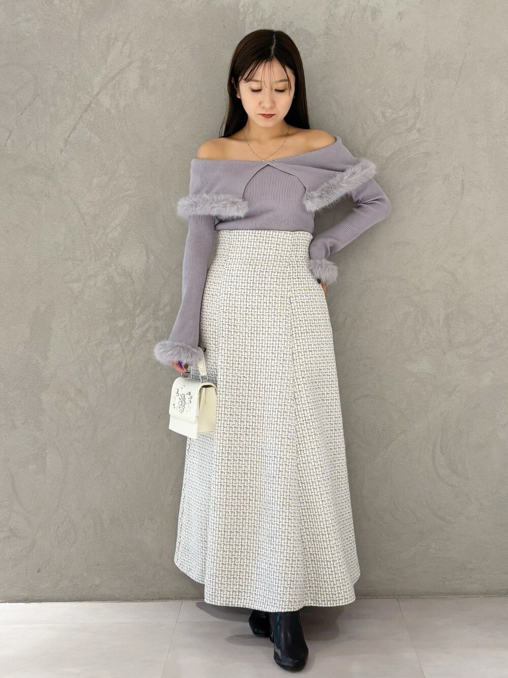 ホワイト系のスカート、ブラック系のブーツ、ホワイト系のショルダーバッグを着用したレディースの冬コーディネートの8枚目の写真