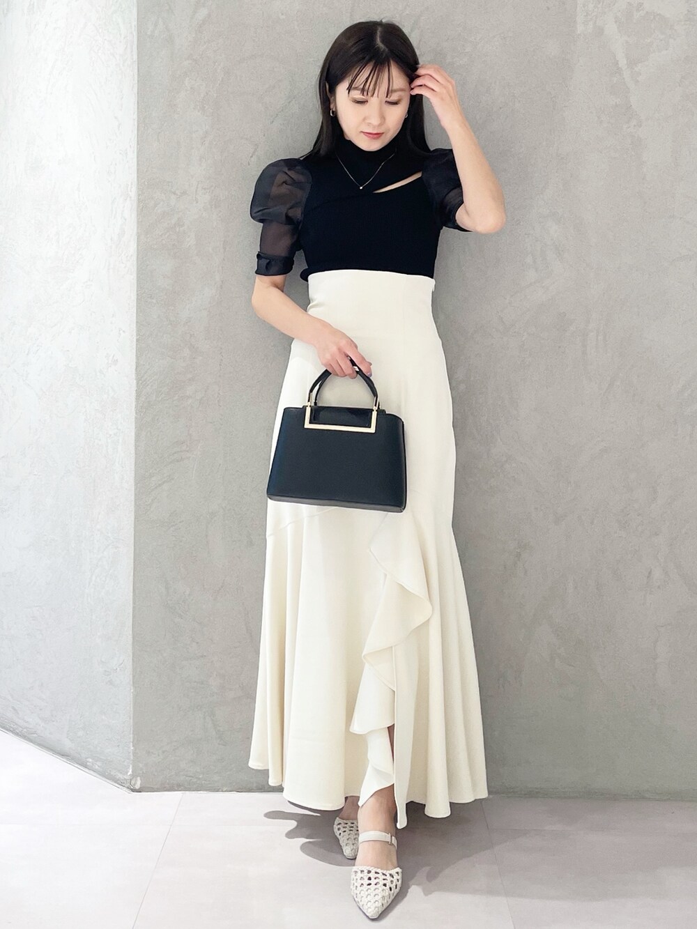 ホワイト系のパンプス、ブラック系のハンドバッグ、ブラック系のニット/セーターを着用したレディースの春コーディネートの4枚目の写真